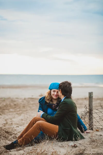 Giovane coppia seduta e in posa sulla spiaggia in autunno — Foto Stock