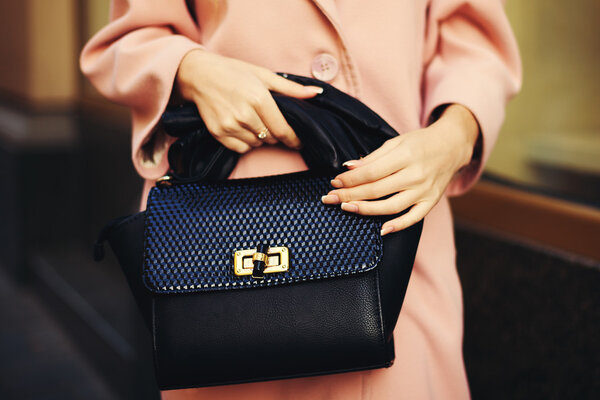 Элегантный наряд. Крупный план черной кожаной сумки сумка в руке стильная женщина. Модная девушка на улице. Женская мода. Toned
