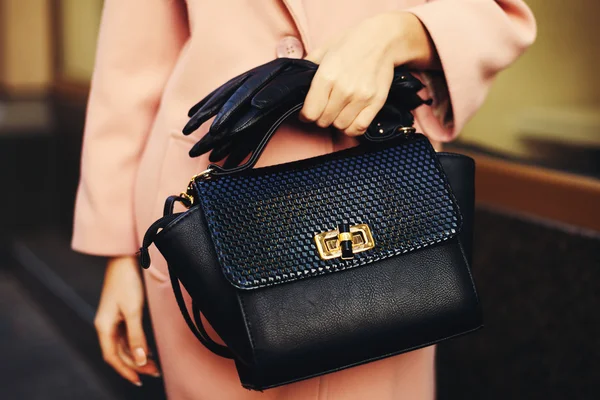 Elegante atuendo. Primer plano del bolso de cuero negro en la mano mujer elegante. Chica de moda en la calle. Moda femenina. Tonificado — Foto de Stock