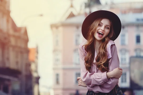 Открытый портрет молодой красивой модной счастливой дамы, позирующей на улице. Модель в стильной шляпе с широкими полями и одежде. Девушка смотрит в камеру. Женская мода. Городской стиль — стоковое фото