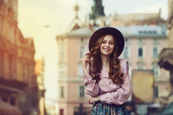 Outdoor portrait of young beautiful fashionable smiling lady posing on old street. Model wearing stylish hat and clothes. Sunny day. Female fashion. City lifestyle. Toned style instagram filters — Stock Photo, Image