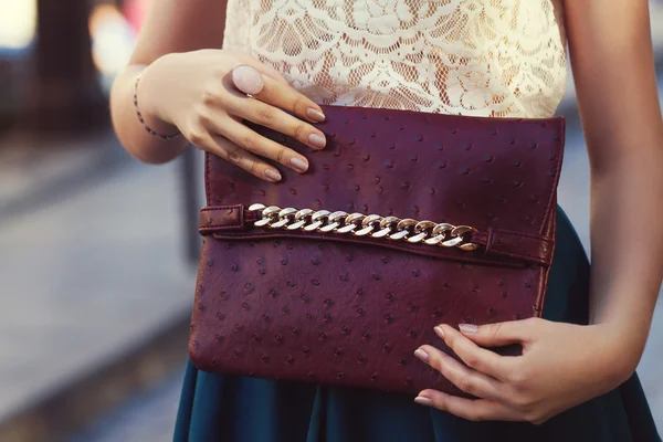 Elegant outfit. Closeup. Leather bag in hands of stylish woman. Fashionable girl on the street. Female fashion.