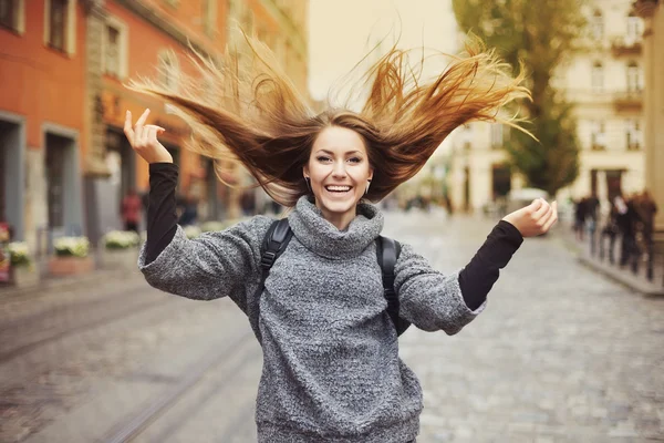 Happy young smiling woman playing with her long beautiful hair. Emotional portrait