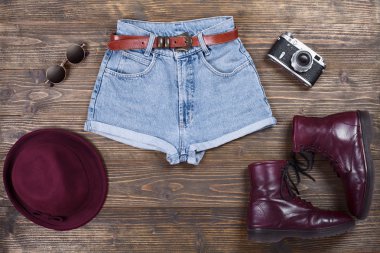 Hipster giysiler ve aksesuarlar, ahşap arka plan üzerinde kadın moda kümesi.
