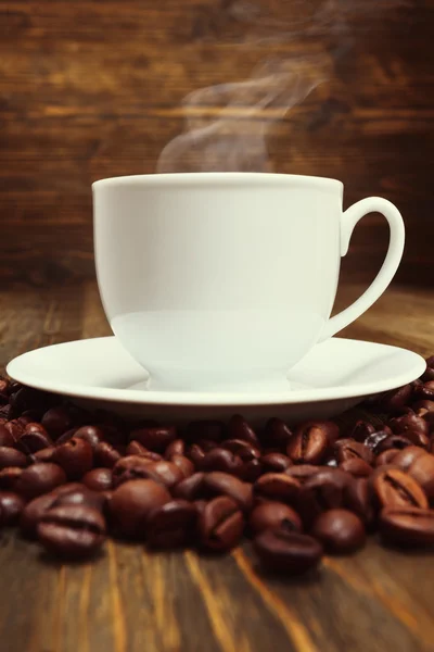 Białe filiżanka kawa i kawa na drewnianym stole. Z bliska — Zdjęcie stockowe