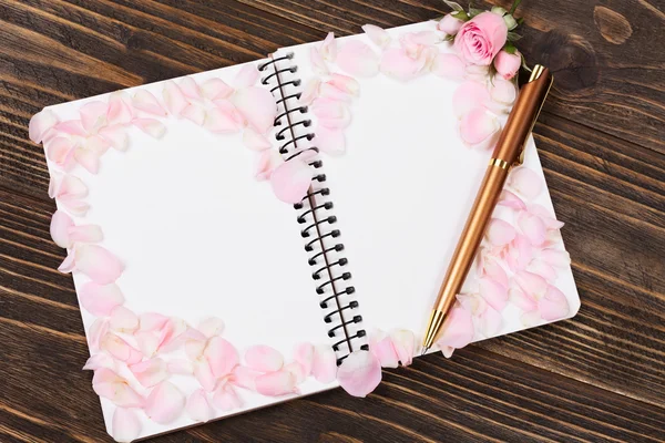 Ahşap masa üstünde açık defter. Gül yaprakları gelen romantik dekor