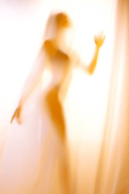 Perdenin arkasındaki kız silueti. Bir kızın soyut ve bulanık görüntüsü