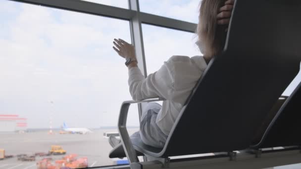 La chica muestra con la mano cómo despega el avión en la terminal del aeropuerto — Vídeos de Stock