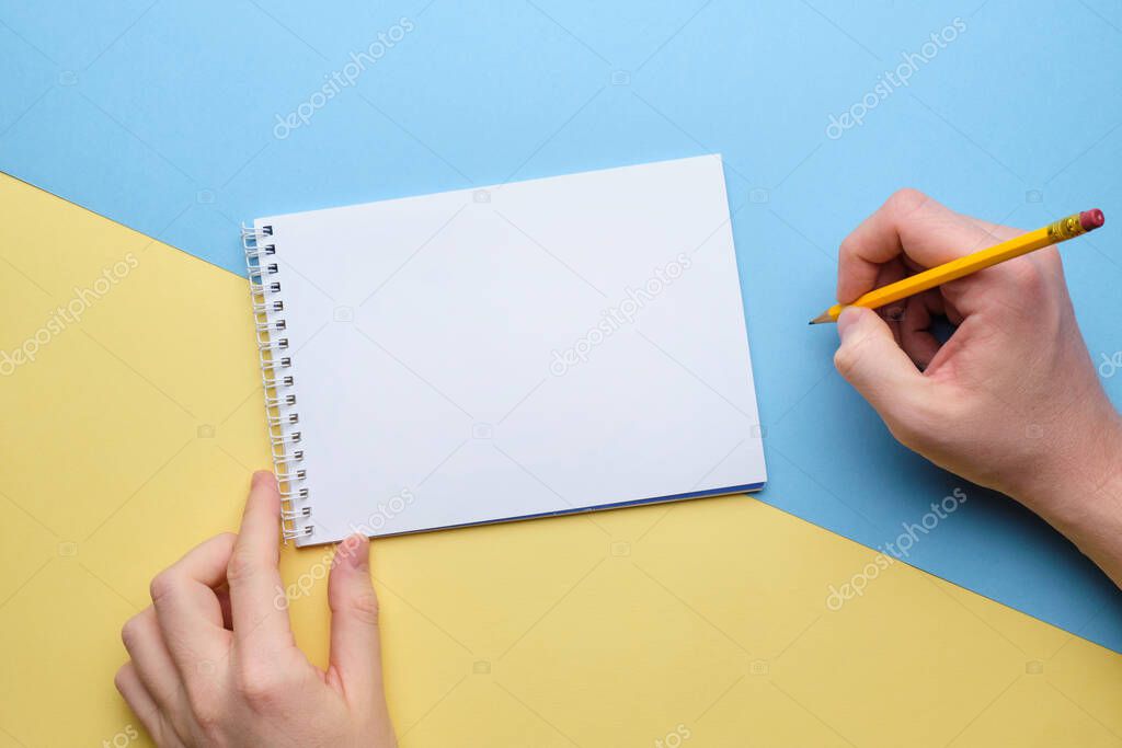 Person makes notes with a pencil in a notebook copy space.
