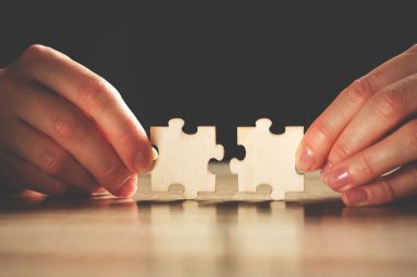 Kişi parmaklarıyla iki yapboz parçası tutar..