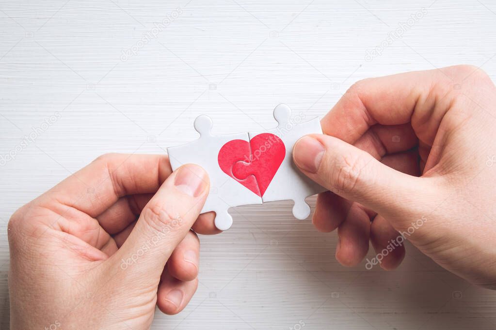 Concept of love from two puzzles with a heart in hands.