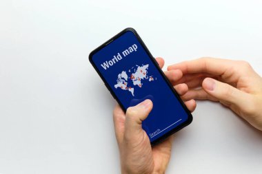 Bir kişi elinde dünya haritalı akıllı bir telefon tutar..