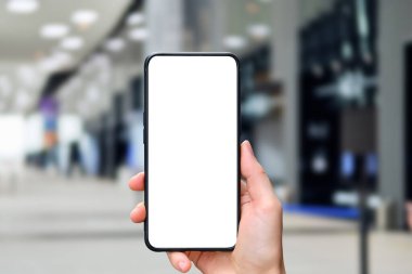 El, ofis binasının arka planı ve fotokopi alanı olan bir akıllı telefonu tutuyor.