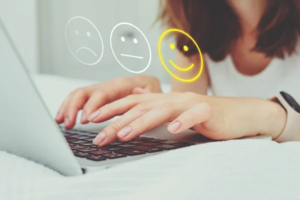Good mood concept made of emoticon and rating. The girl puts grades on the Internet using a laptop
