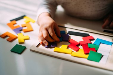A child playing a colored puzzle on the table.