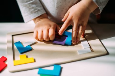 The toddler collects in a colored puzzle on the table.