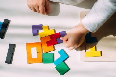 The toddler connects the pieces of the colored puzzle.