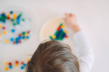 Child playing mosaic on table at home with blur.