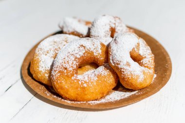 Tahta bir masadaki karton tabakta pudra şekerli tatlı..