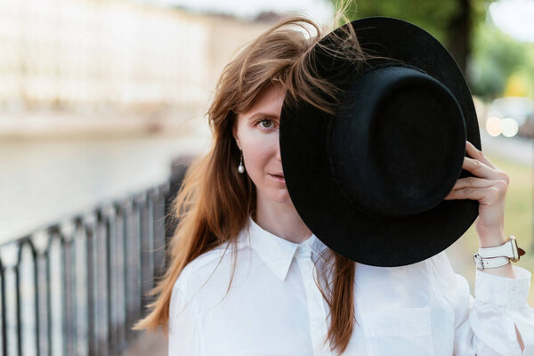 Mysterious Caucasian girl covers half of her face with a hat.