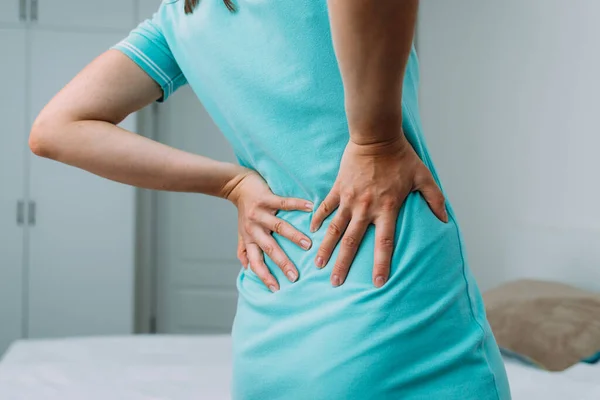 Caucasian woman suffering from lower back pain at home.