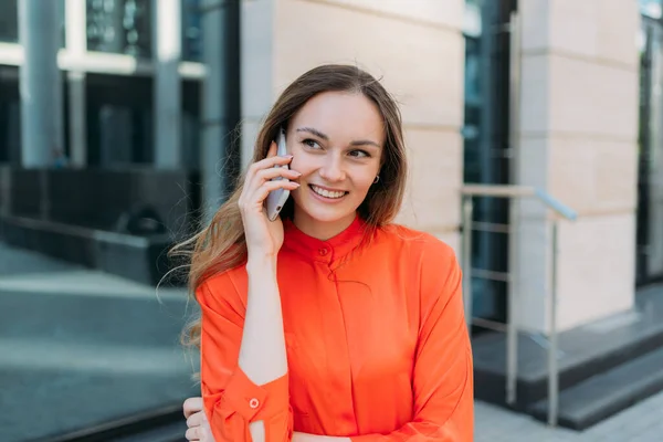 Young woman talking with a smile on the phone in the city.