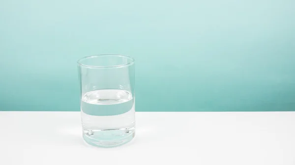 Половина порожньої або наполовину повної склянки води на білому столі . — стокове фото