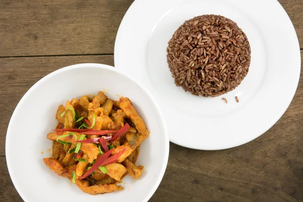 La deliciosa comida casera de curry paneang tailandés (curry de crema de coco de cacahuete de cerdo o curry panang con cerdo) y arroz integral oscuro cocido en el plato blanco — Foto de Stock