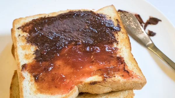The close up of tasty bread toast and strawberry jam with chocolate spread on white plate. — Stock Photo, Image