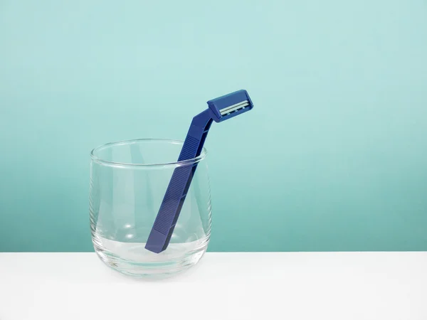The dark blue plastic razor and round glass — Stock Photo, Image