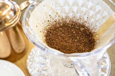 Organik kahve çekirdeklerinin makrosu sabah kahvesi için sıcak kahve damlatıcısını kağıt filtreye sardı..