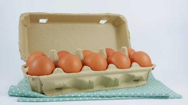 Die frischen Hühnereier auf der Pappschachtel und der Baumwollstoff. — Stockfoto