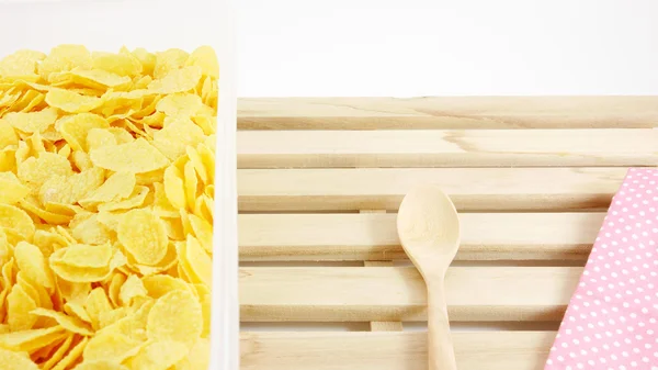 Tasty golden corn flakes in plastic container box on wooden tray — Stock Photo, Image