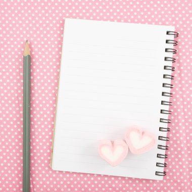 Güzel pembe kalp şekerleme ve küçük beyaz not defteri ve kalem