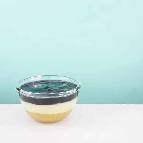 A házi áfonyás sajttorta a kis üveg tálba, a fehér asztal. — Stock Fotó