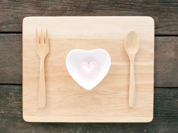Ceramiczne serce w kształcie misy i różowy Zefir i drewnianą łyżką widelcem na deski drewniane — Zdjęcie stockowe