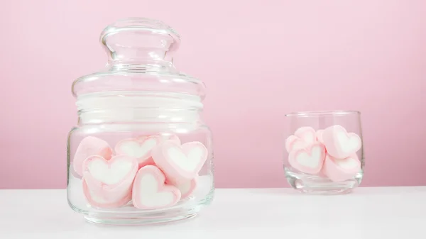 Os marshmallows de coração rosa encantador em frasco de vidro pequeno e vidro redondo pequeno — Fotografia de Stock