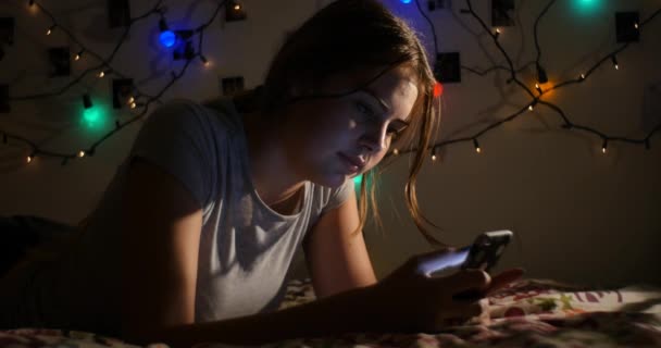 Young teenage girl relaxing on bed interacting with social media on mobile smart — Stock Video