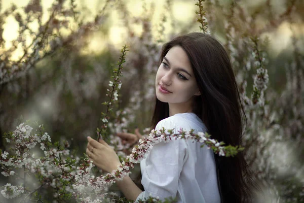 一个漂亮的姑娘站在开花的植物旁边 — 图库照片
