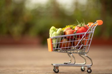 grocery cart filled with vegetables, tomatoes and cucumbers on the street