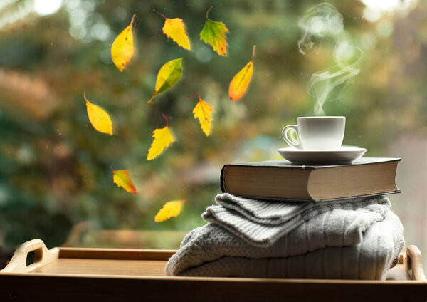 autumn mood at the window with leaves a book and a cup of coffee