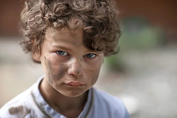Грязный бездомный мальчик смотрит сквозь глаза полные слез — стоковое фото