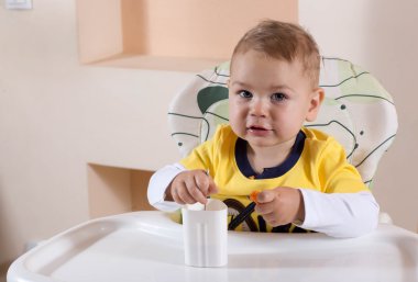 Küçük oğlan kahvaltıda yoğurt yiyor