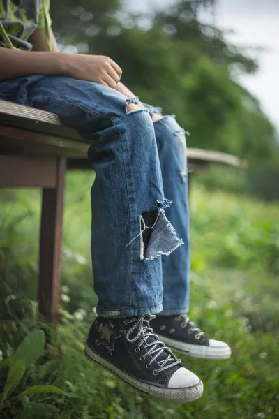 Πόδια του ένας άστεγος άντρας στο βρώμικο, σκισμένα τζιν — Φωτογραφία Αρχείου