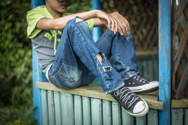 Foto sucio sin hogar chico con pantalones vaqueros rotos —  Fotos de Stock