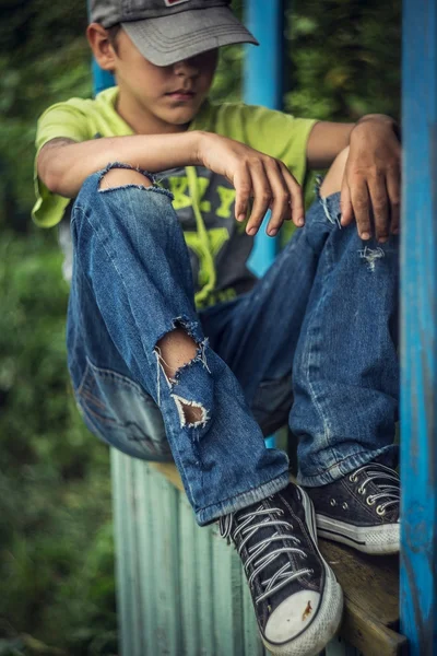 Foto sucio sin hogar chico con pantalones vaqueros rotos — Foto de Stock