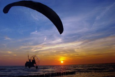 Batan güneşin arka planına karşı paraglider