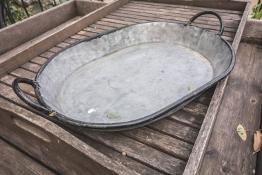 Arka bahçenin arka planında iki tahta saplı metal yalak. Kırsal ihtiyaçlar için çelik leğen.