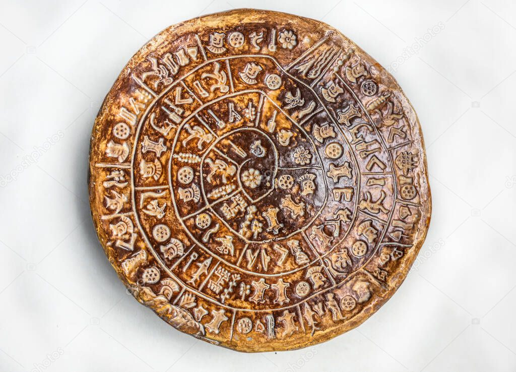The Phaistos Disc (also spelled Phaistos Disk, Phaestos Disc) is a disk of fired clay from the Minoan palace of Phaistos on the island of Crete. The disk isolated on white background covered on both sides with a spiral of stamped symbols.
