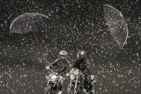 Through snow and rain rushing two motorcyclists